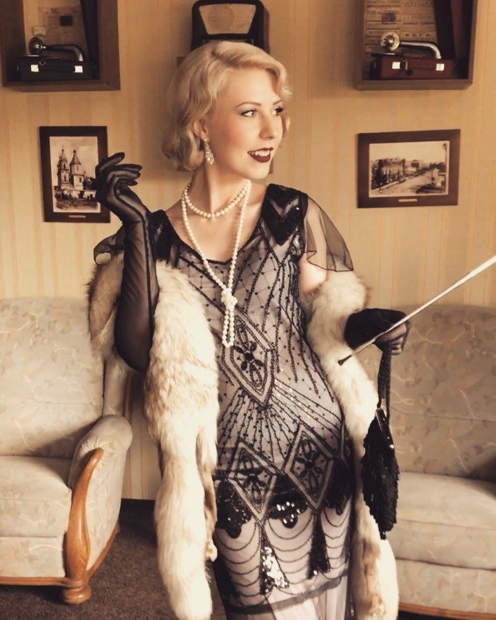 Woman in a 1920s beaded long dress with white fur stole and pearls.