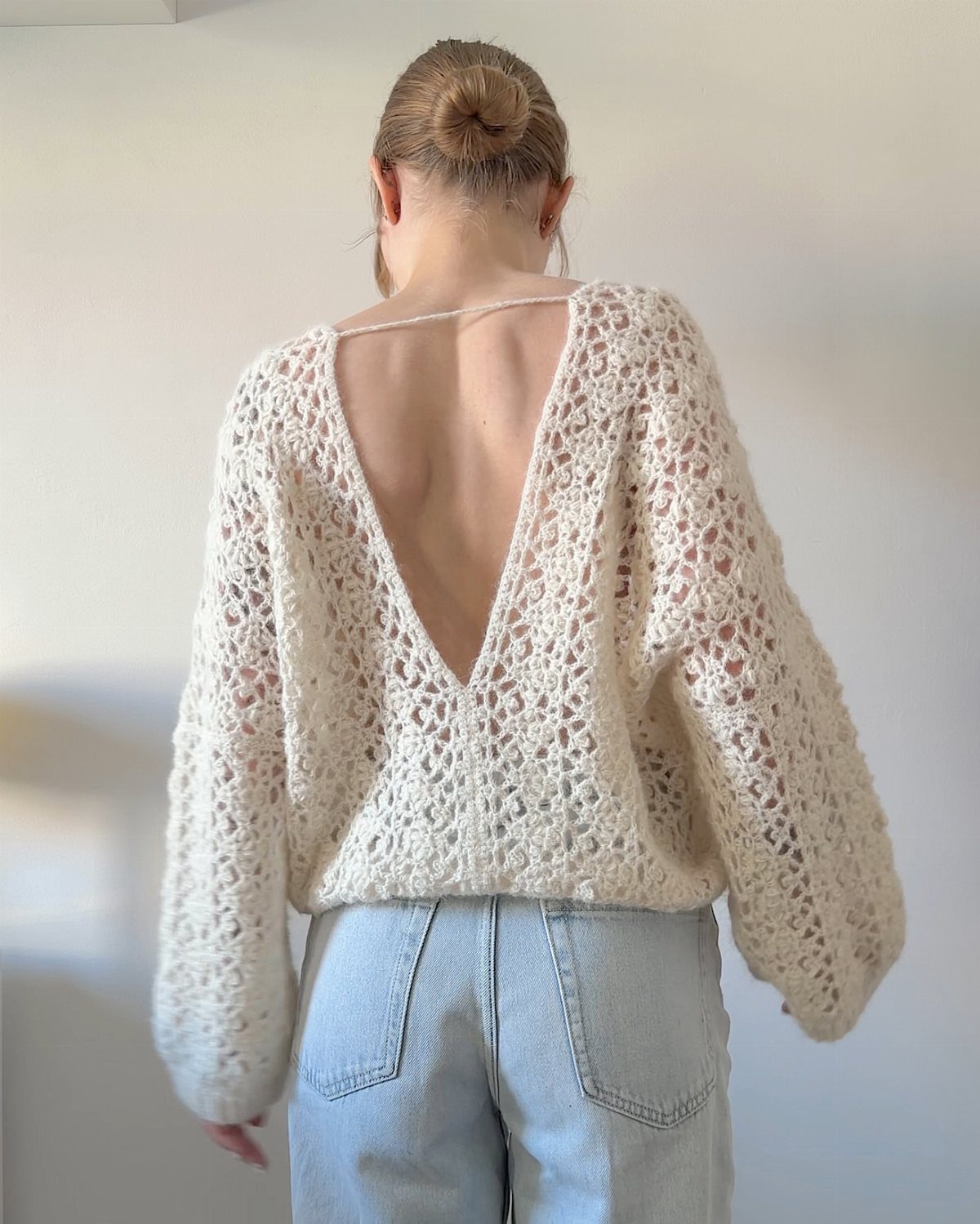 Cream crochet top with a deep V-back worn with light blue jeans.