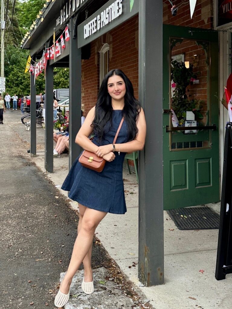 Woman wearing a dark blue denim mini dress and brown crossbody bag outdoors.
