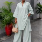 Woman wearing a mint green tunic and matching wide-leg tailored trousers with beige heels.