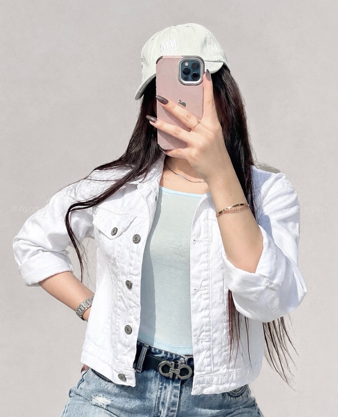 Person wearing a white denim jacket and blue skinny jeans taking a selfie.