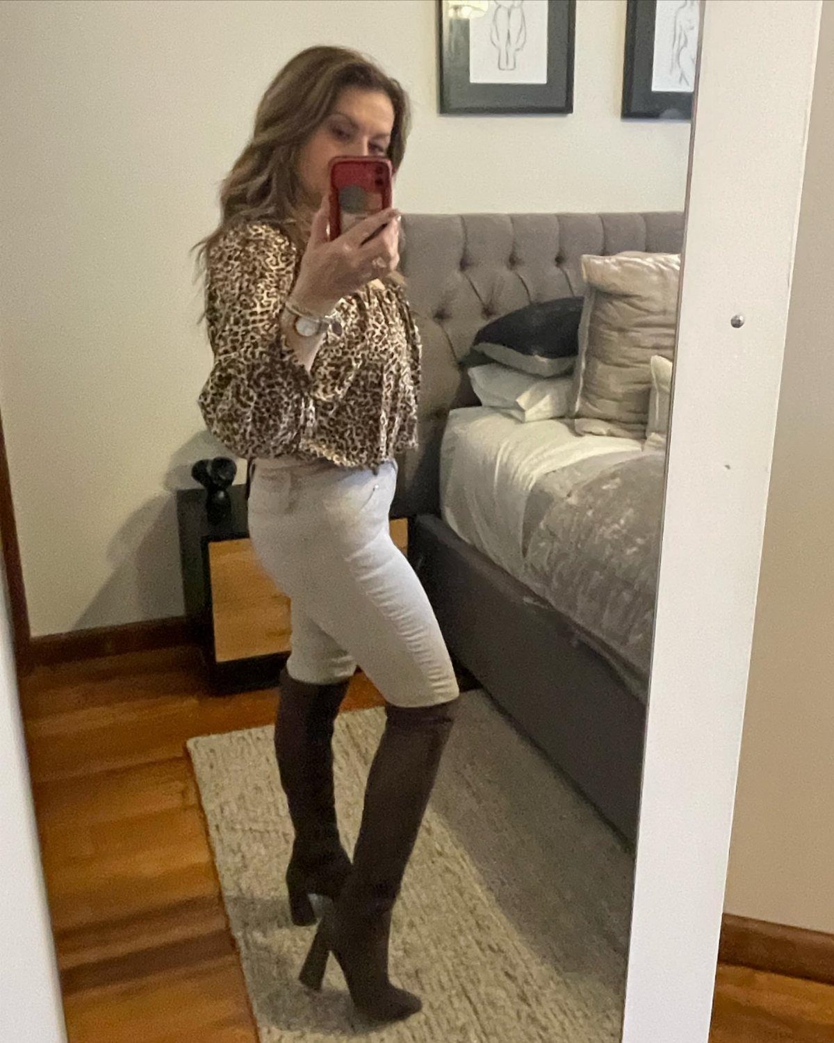 Woman wearing leopard print blouse, light pants, and tall brown heeled boots.