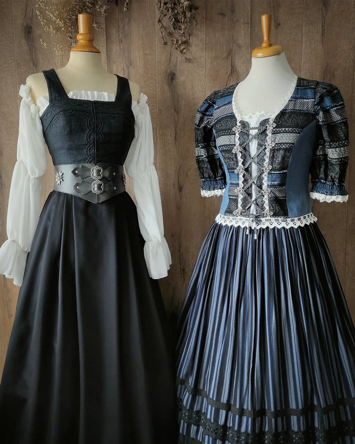 Two medieval style dresses on mannequins, one black and one blue striped.
