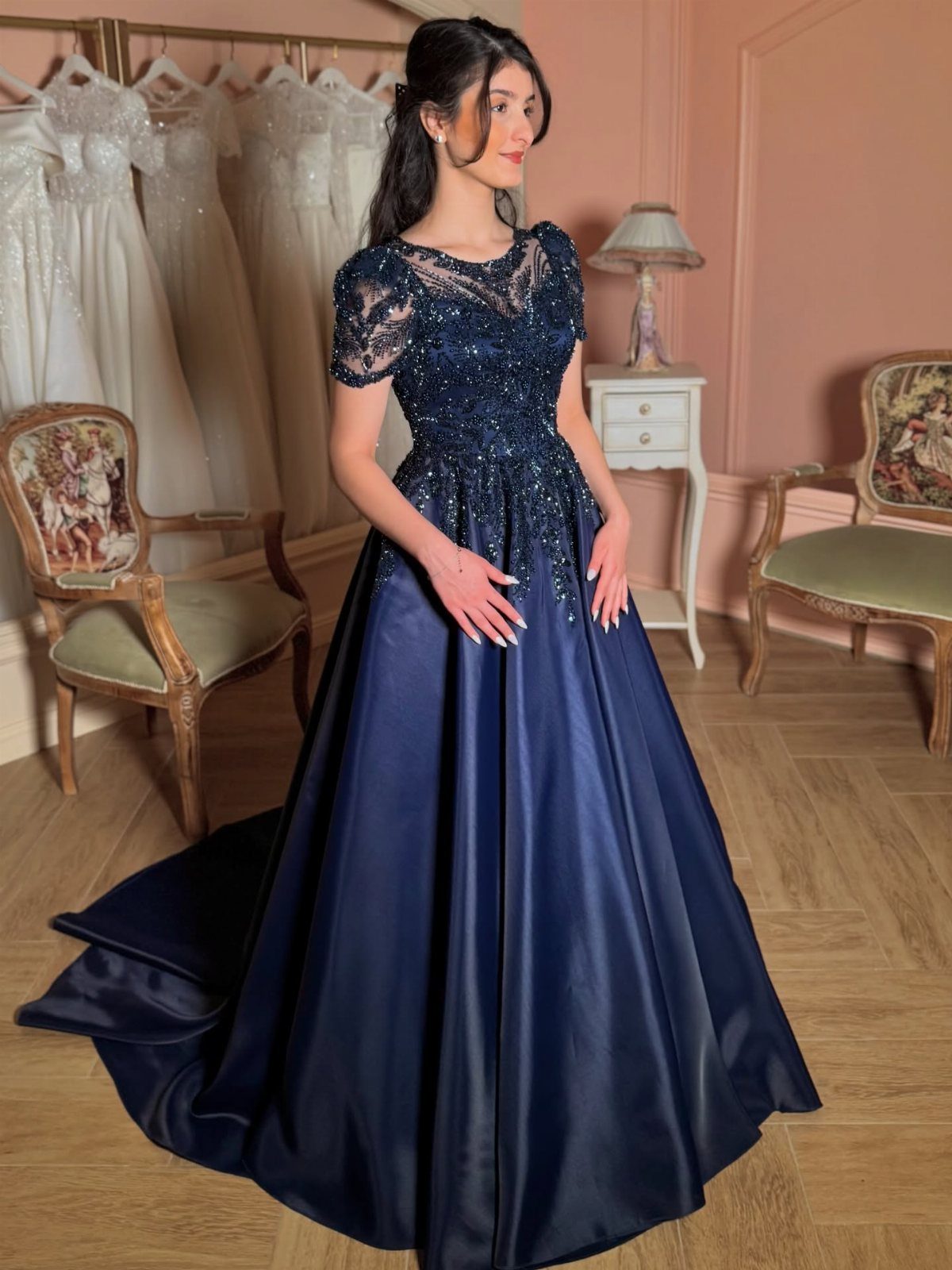 Woman wearing a navy blue ball gown with beaded bodice in a bridal shop