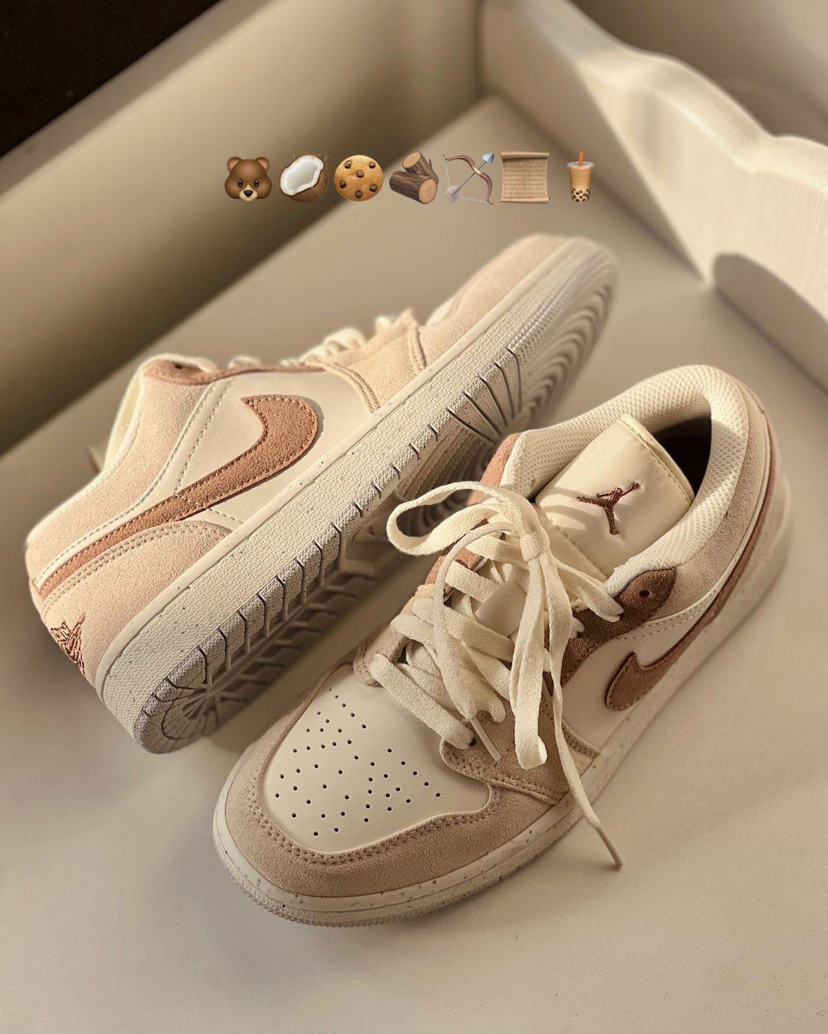 Beige and tan Nike Air Jordan sneakers with white laces on a white surface.