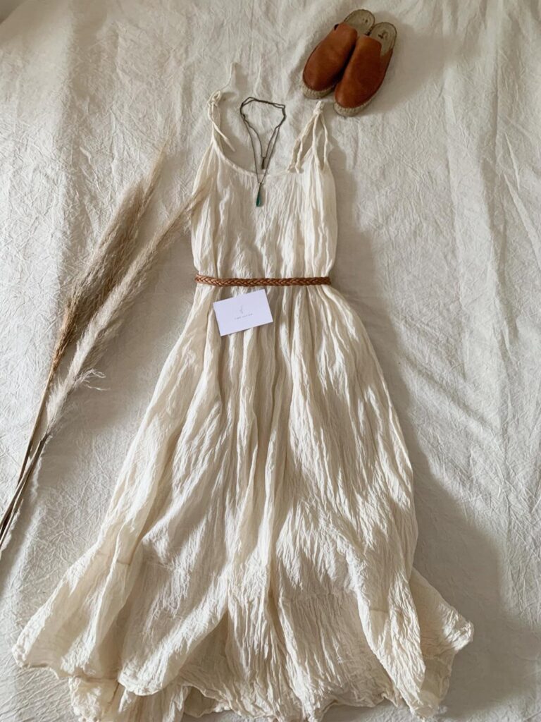White bohemian maxi dress with a brown belt and leather mules on white fabric