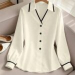 White collared work shirt with black trim and buttons on a hanger.