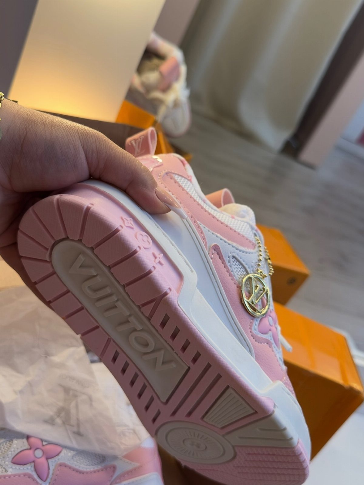 Pink and white designer sneaker with VUITTON embossed on the sole and gold charm.