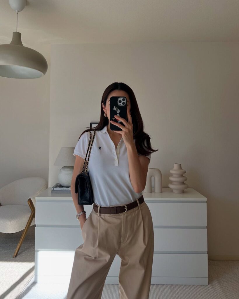 Woman wearing a white short-sleeve polo shirt and beige high-waisted trousers.