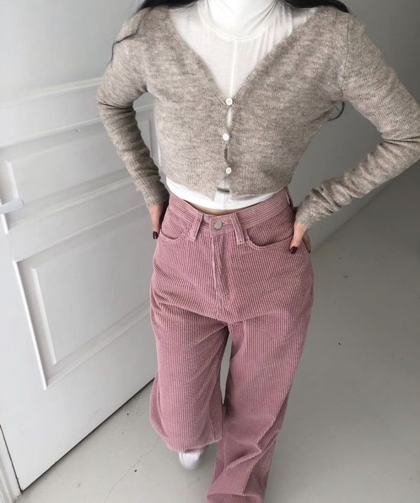 Person wearing a beige cropped cardigan and high-waisted pink corduroy trousers.
